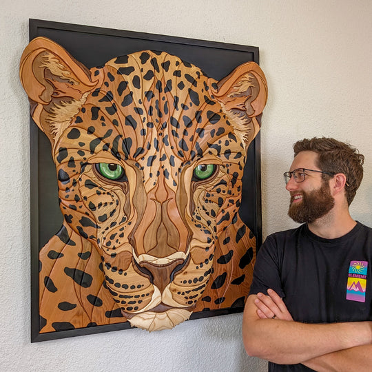 Alex Jepson contemplating his jaguar wood sculpture, showcasing intricate craftsmanship and nature-inspired art.